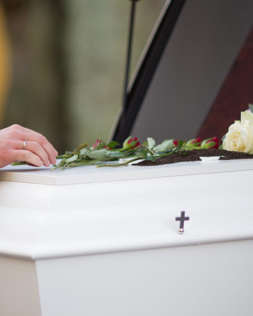 Closeup shot of a person hand on a casket with a blurred background A closeup shot of a person hand on a casket with a blurred background