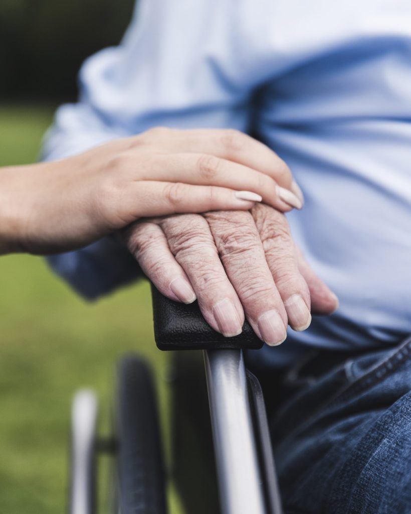 Young woman touching senior man’s hand, close-up Young woman touching senior man's hand, close-up